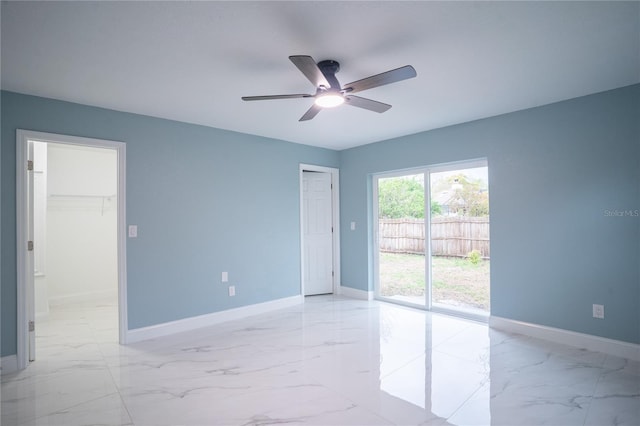 spare room with marble finish floor, a ceiling fan, and baseboards