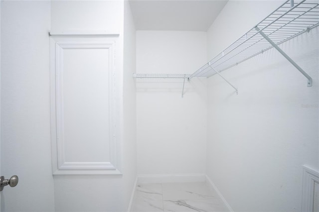 walk in closet featuring marble finish floor