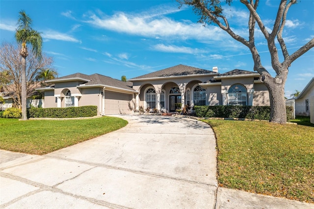 mediterranean / spanish home featuring a garage, driveway, a front lawn, and stucco siding