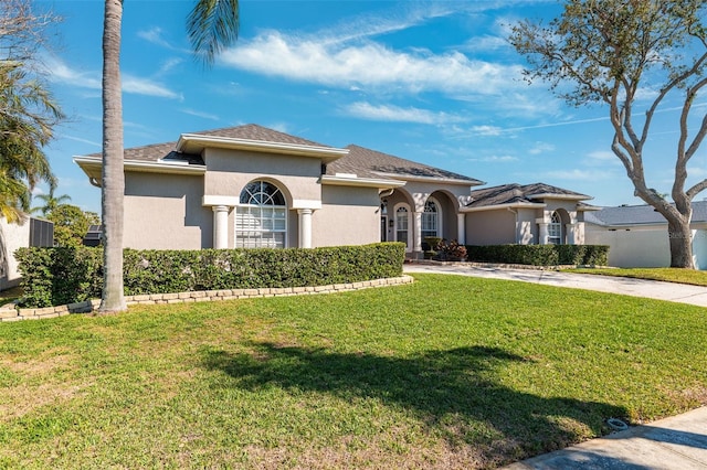 mediterranean / spanish house with concrete driveway, a front lawn, and stucco siding