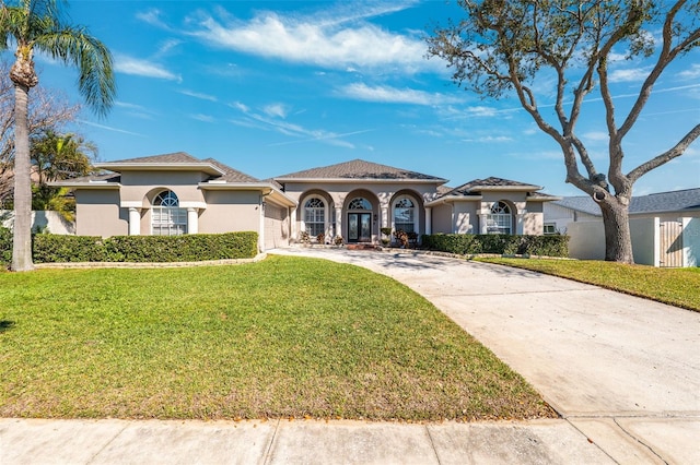 mediterranean / spanish-style house with driveway, stucco siding, and a front yard