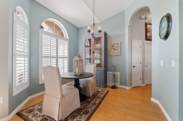 dining room with arched walkways, a notable chandelier, visible vents, baseboards, and light wood-style floors