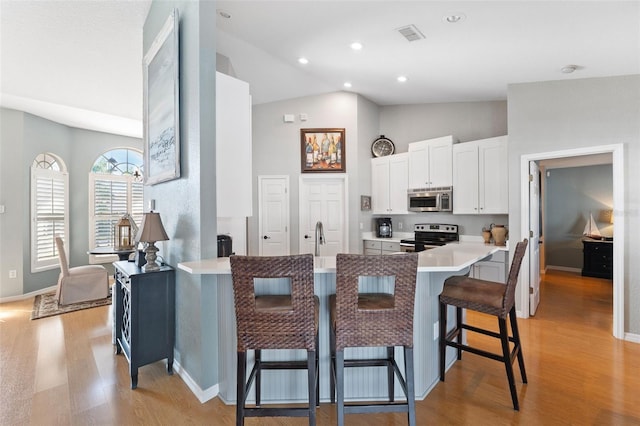 kitchen featuring stainless steel appliances, a breakfast bar, a peninsula, and light wood finished floors