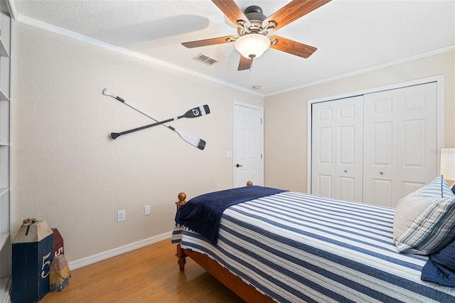 bedroom featuring baseboards, visible vents, wood finished floors, and ornamental molding