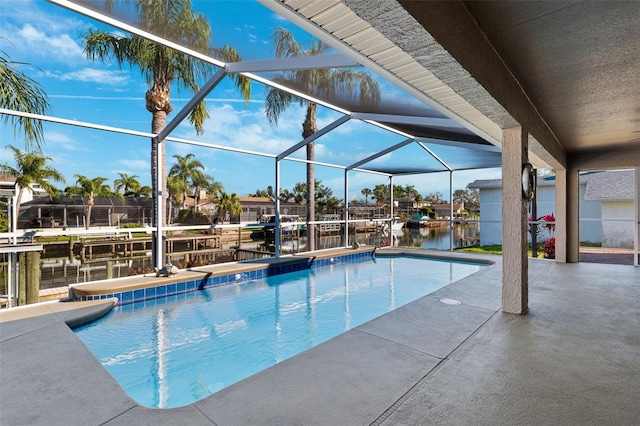 outdoor pool featuring a dock, glass enclosure, a patio area, and a water view