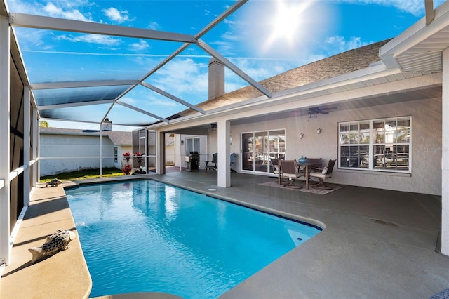 pool featuring ceiling fan, glass enclosure, and a patio area