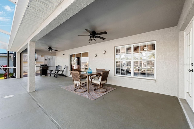 view of patio / terrace with glass enclosure, outdoor dining space, a grill, and a ceiling fan