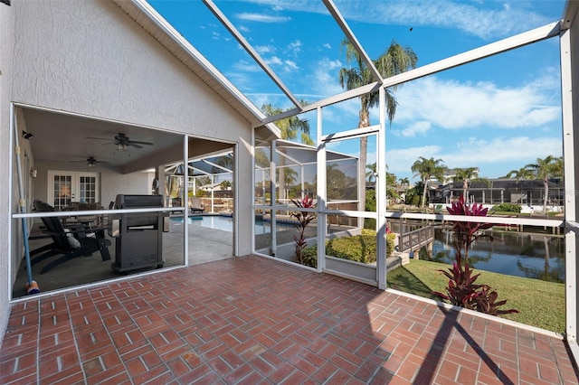 unfurnished sunroom featuring lofted ceiling, a water view, and a ceiling fan