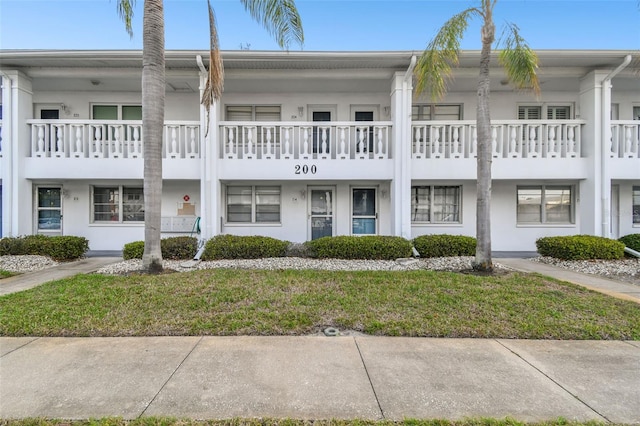 multi unit property with a front lawn and stucco siding