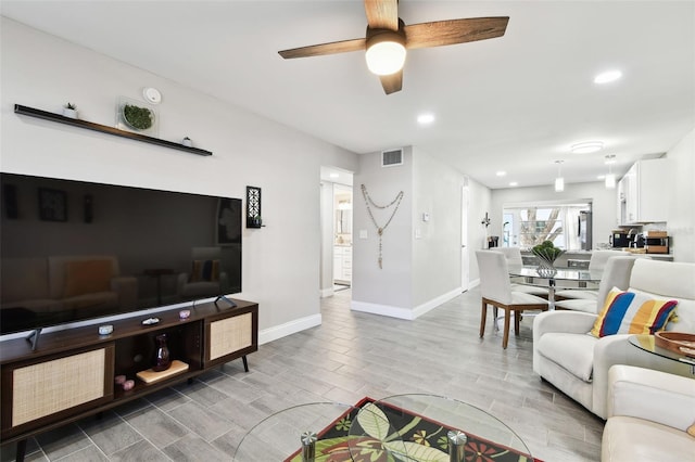 living area with recessed lighting, wood finish floors, a ceiling fan, visible vents, and baseboards