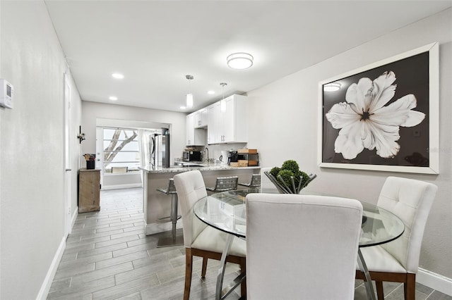 dining space featuring wood tiled floor, baseboards, and recessed lighting