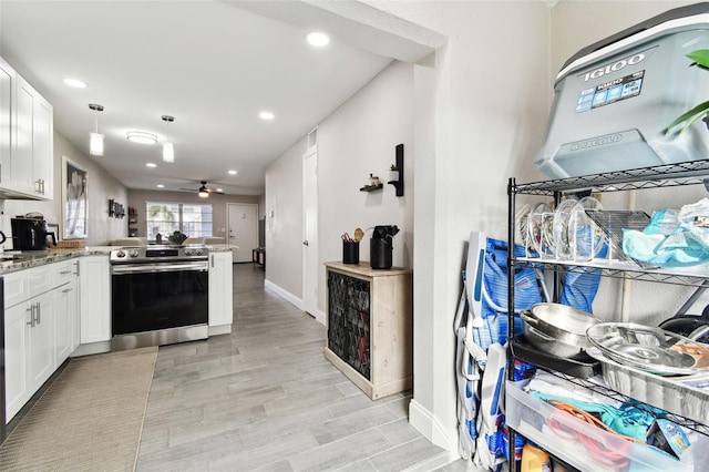 kitchen featuring a peninsula, light stone countertops, white cabinetry, and stainless steel range with electric cooktop
