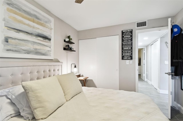 bedroom featuring baseboards, visible vents, a ceiling fan, wood finished floors, and a closet
