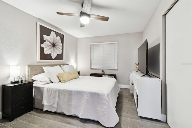 bedroom with ceiling fan, baseboards, and wood finish floors