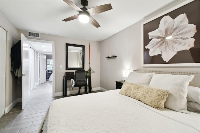 bedroom with baseboards, visible vents, a ceiling fan, and wood finished floors