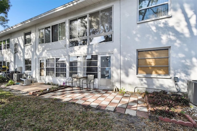rear view of property with central AC, a patio area, and stucco siding