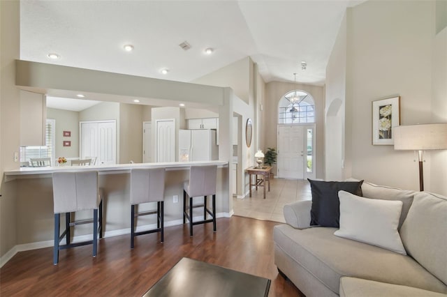 living area with visible vents, baseboards, dark wood finished floors, and vaulted ceiling