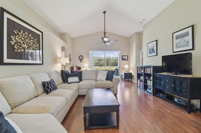 living room with a ceiling fan, wood finished floors, baseboards, arched walkways, and vaulted ceiling