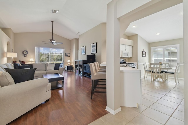 living room with lofted ceiling, light tile patterned floors, a healthy amount of sunlight, and visible vents