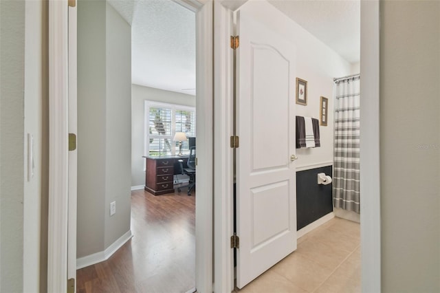 corridor featuring a textured ceiling and baseboards