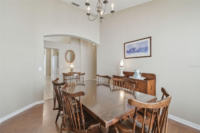 dining room featuring visible vents, wood finished floors, arched walkways, baseboards, and a chandelier