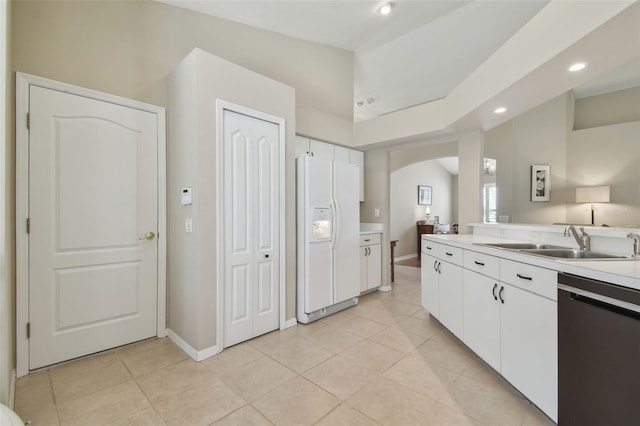 kitchen featuring dishwasher, white refrigerator with ice dispenser, arched walkways, white cabinets, and a sink