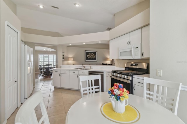 kitchen with a sink, white appliances, an inviting chandelier, light countertops, and light tile patterned floors