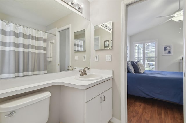 ensuite bathroom with ceiling fan, vaulted ceiling, ensuite bathroom, wood finished floors, and vanity