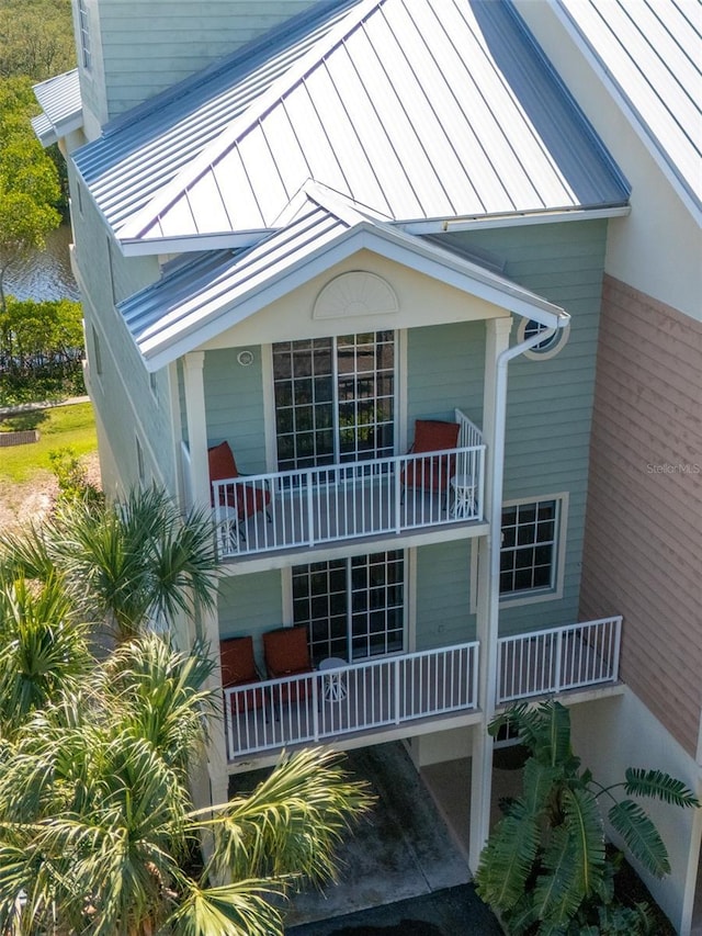 view of side of home featuring a balcony, a standing seam roof, metal roof, and covered porch