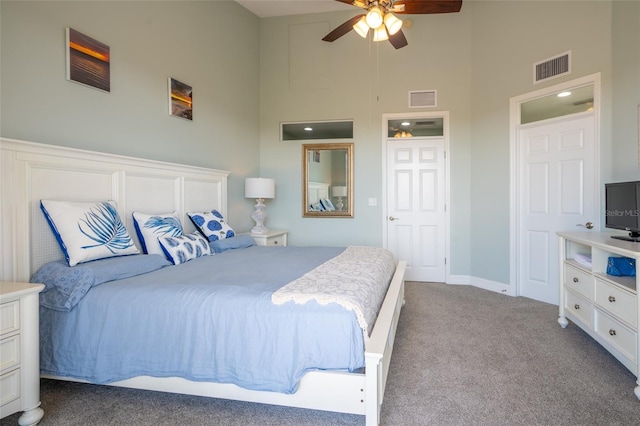 bedroom with carpet floors, baseboards, a high ceiling, and visible vents