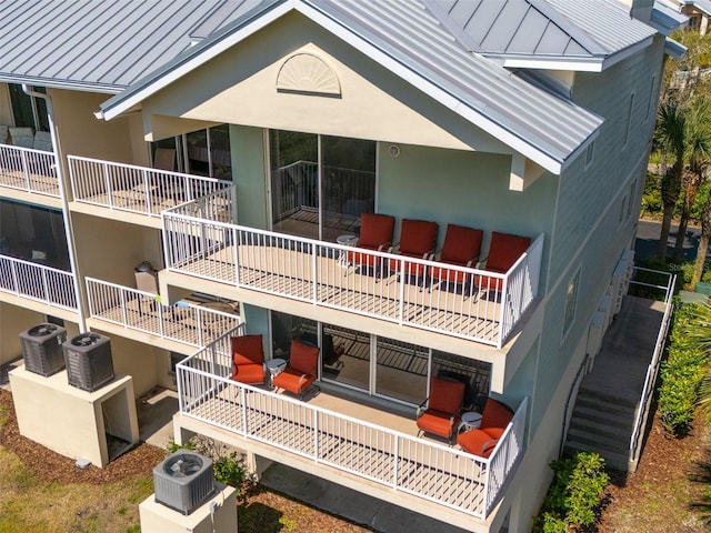 back of house with a patio, stucco siding, a standing seam roof, metal roof, and stairs