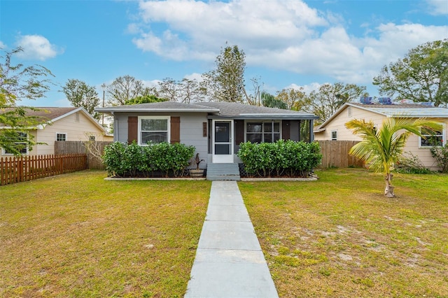 bungalow-style home featuring entry steps, a sunroom, a fenced backyard, and a front yard