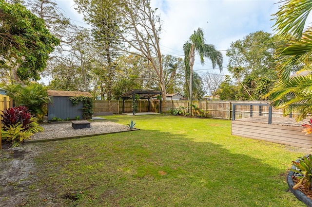 view of yard featuring a deck, an outbuilding, a fenced backyard, a storage shed, and a pergola