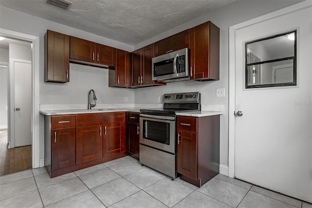 kitchen with light tile patterned flooring, a sink, visible vents, light countertops, and appliances with stainless steel finishes