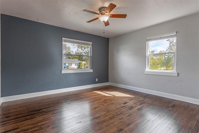 spare room with dark wood-style floors, baseboards, and a textured wall