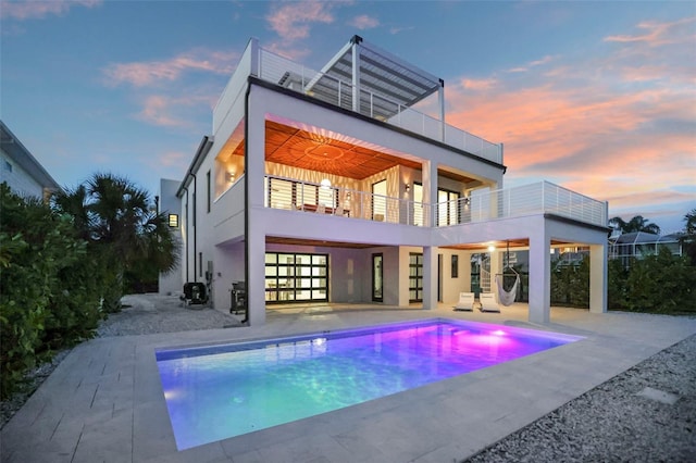 back of house featuring a garage, a patio area, a balcony, and stucco siding