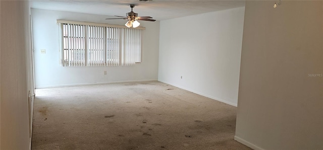 spare room featuring baseboards, a ceiling fan, and light colored carpet