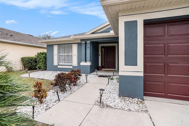 doorway to property with stucco siding and an attached garage