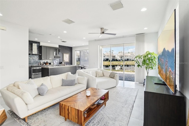 living room with ceiling fan, visible vents, and recessed lighting