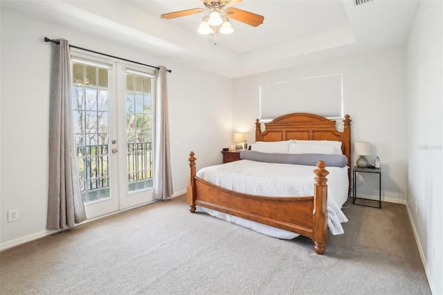 bedroom featuring access to exterior, baseboards, a tray ceiling, and french doors