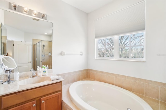 bathroom with a stall shower, visible vents, a bath, and vanity