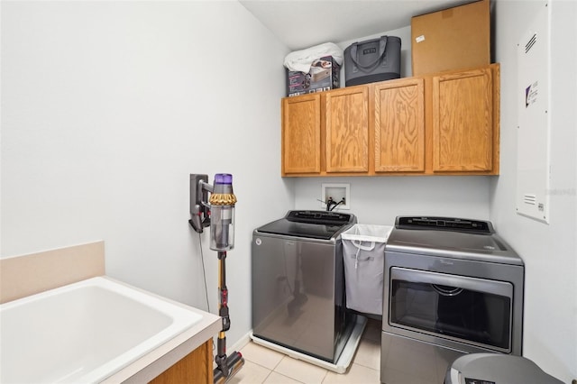 clothes washing area with cabinet space, washing machine and clothes dryer, and light tile patterned flooring