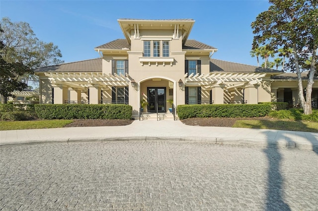 view of front of home featuring a tiled roof, a pergola, and stucco siding