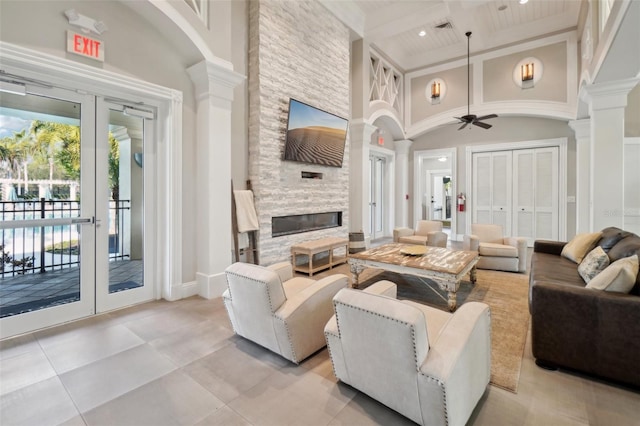 living room with french doors, a stone fireplace, and decorative columns