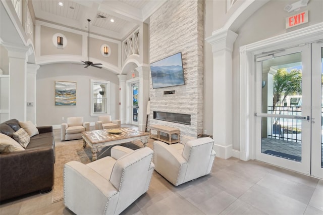 living room featuring beam ceiling, a fireplace, decorative columns, a towering ceiling, and coffered ceiling