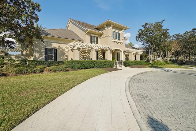 view of front of house with stucco siding, decorative driveway, and a front yard