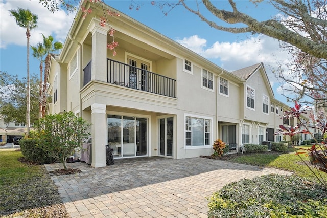 rear view of property featuring a patio area, a balcony, and stucco siding