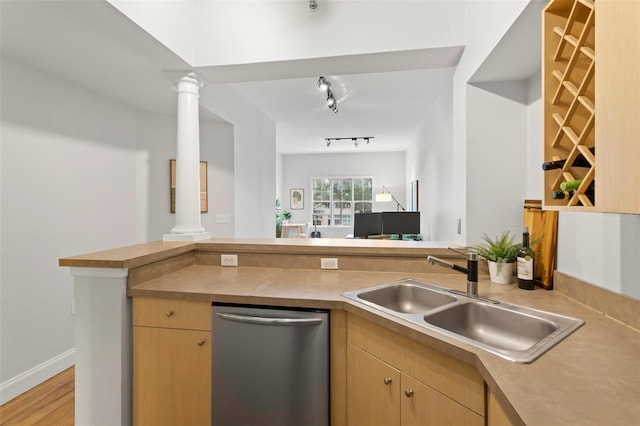 kitchen featuring dishwasher, open floor plan, a sink, and ornate columns