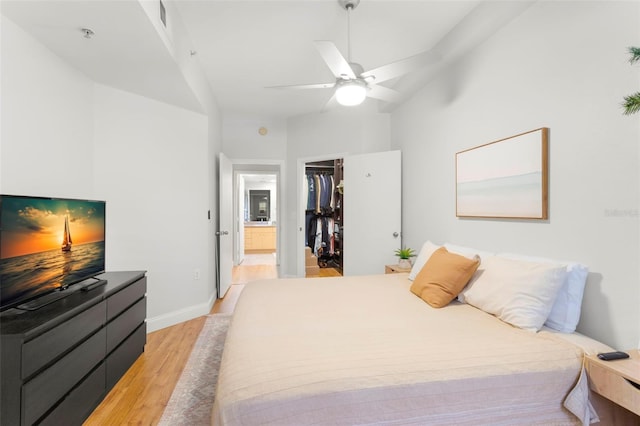 bedroom featuring a closet, a spacious closet, a ceiling fan, light wood-type flooring, and baseboards