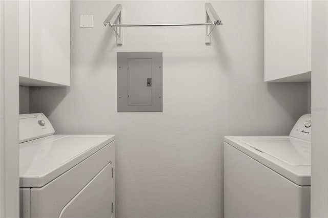 washroom with electric panel, cabinet space, and washer and clothes dryer